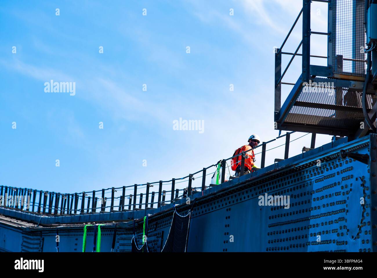 Men wearing harnesses, helmets and other PPE work on the steel arch of the Sydney Harbour Bridge in Australia Stock Photo
