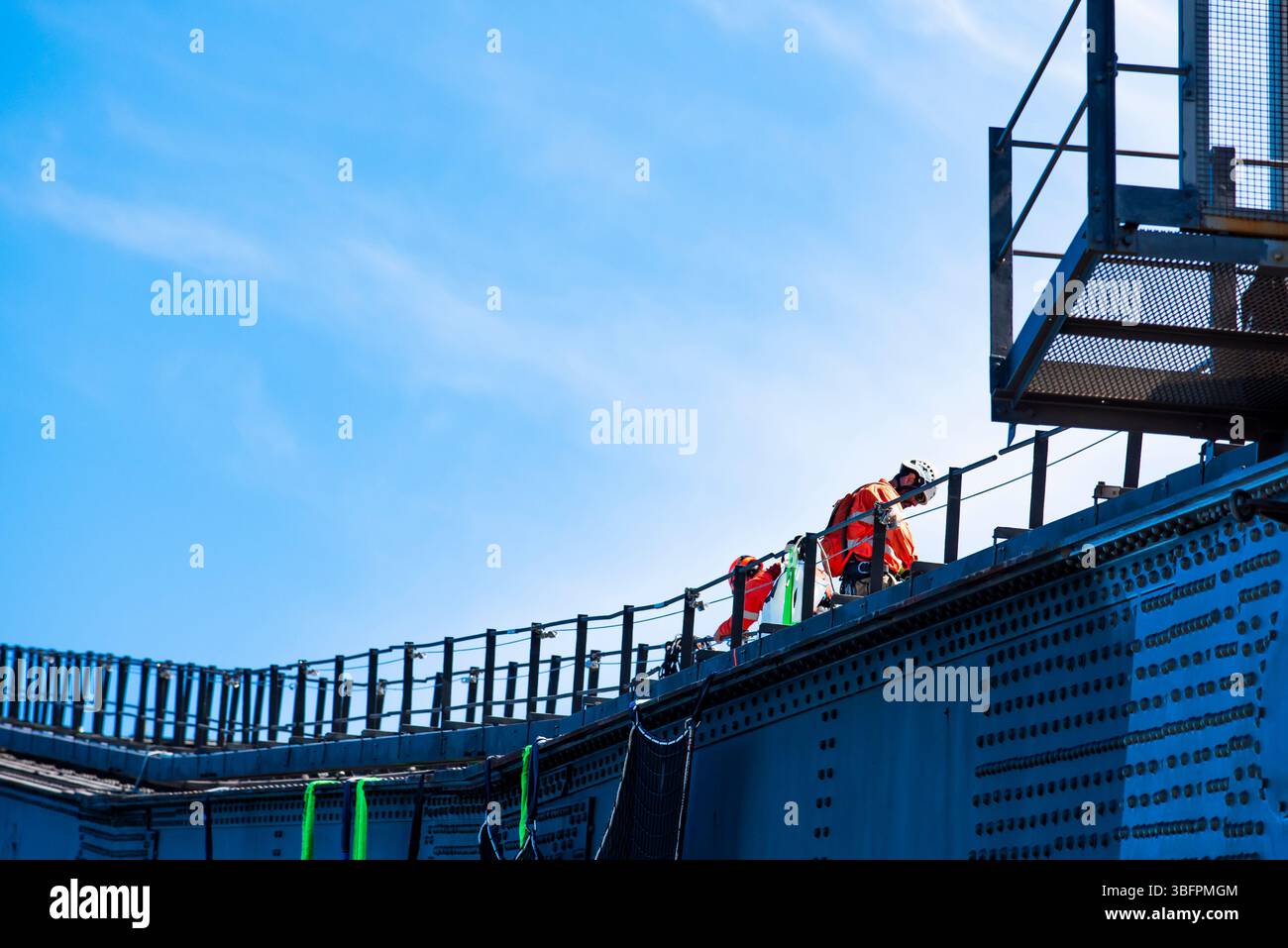 Men wearing harnesses, helmets and other PPE work on the steel arch of the Sydney Harbour Bridge in Australia Stock Photo