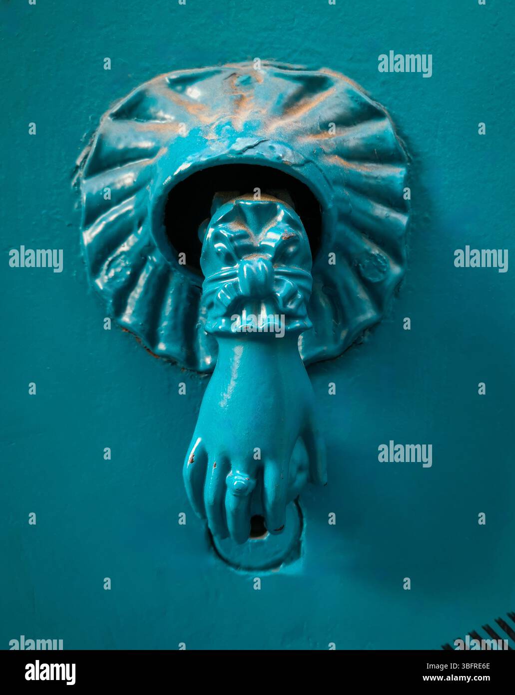 This unique door knocker features a lion's paw design with detailed craftsmanship. Its turquoise color contrasts wonderfully with the blue background Stock Photo