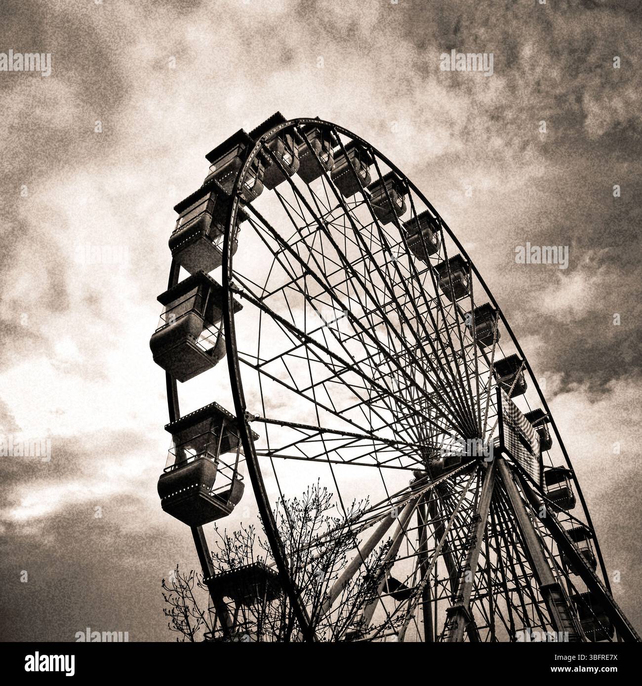 A towering Ferris wheel emerges against a swirling, moody sky during twilight hours - Smartphone Captured Stock Image