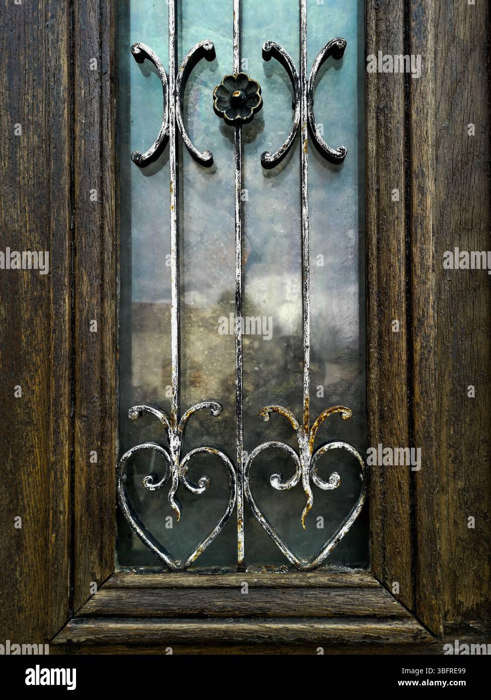 Craftsmanship shines through this wooden door, featuring beautiful metal designs and colorful glass panels. Auvergne. France - Smartphone Captured Stock Image