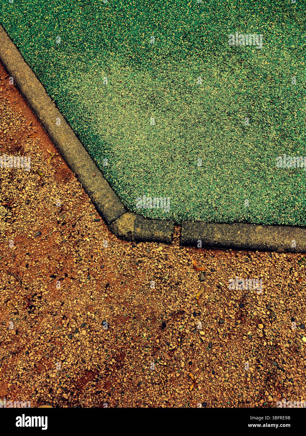 This detailed view captures the unique transition of a playground surface from vibrant green rubber to brown dirt during midday. - Smartphone Captured Stock Image This detailed view captures the unique transition of a playground surface from vibrant green rubber to brown dirt during midday. - Smartphone Captured Stock Image