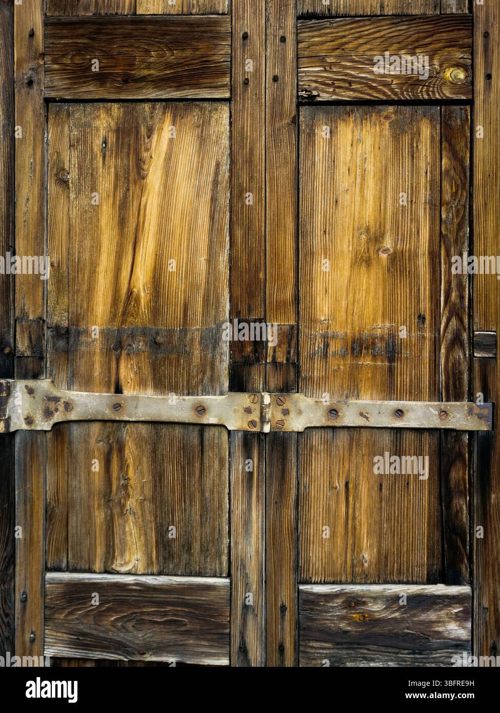 Close-up view reveals a weathered wooden door adorned with intricate patterns and robust metal accents - Smartphone Captured Stock Image Close-up view reveals a weathered wooden door adorned with intricate patterns and robust metal accents - Smartphone Captured Stock Image