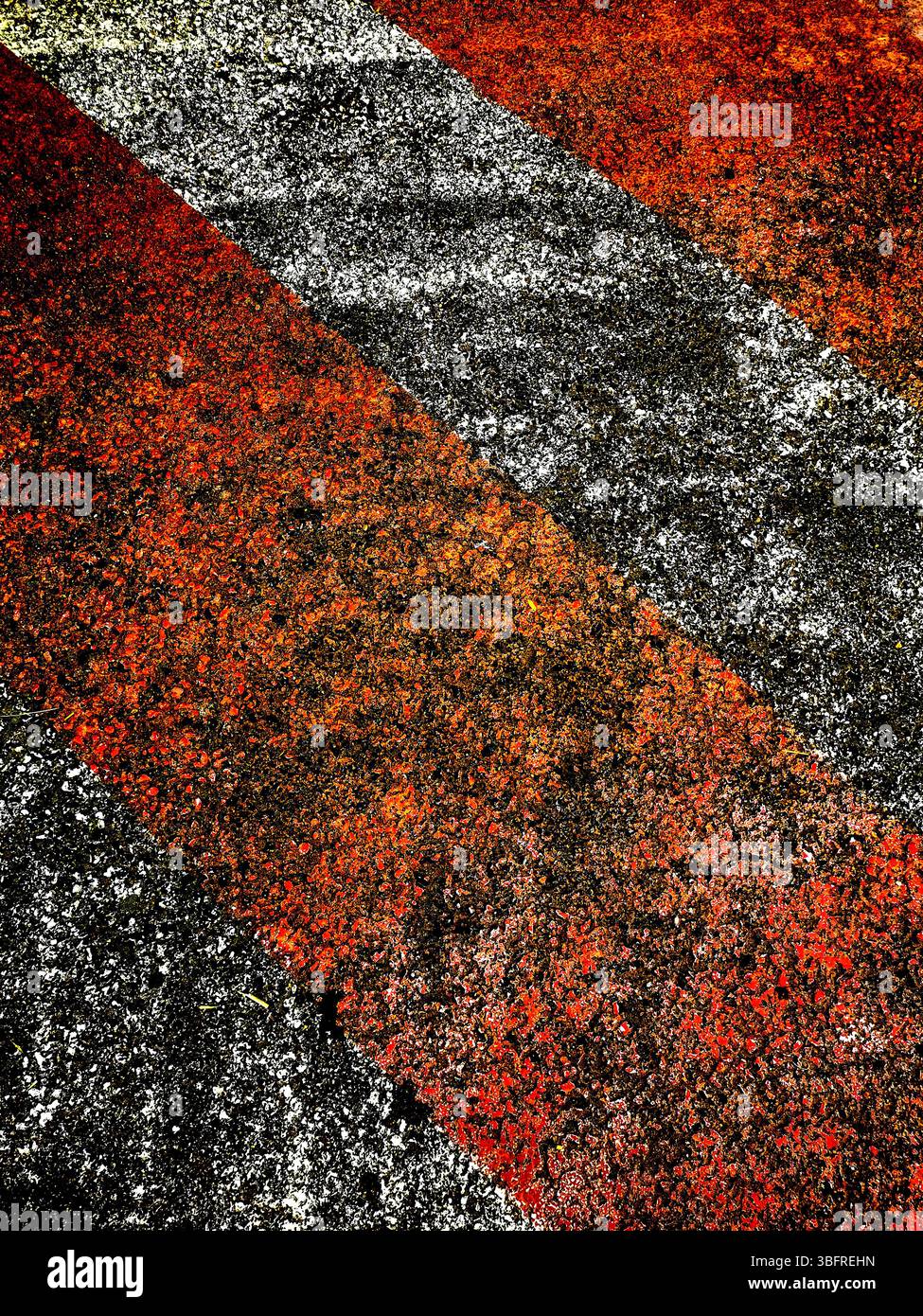 Bold red and black lines create an eye-catching pattern on a rough surface, illuminated by warm late afternoon light - Smartphone Captured Stock Image