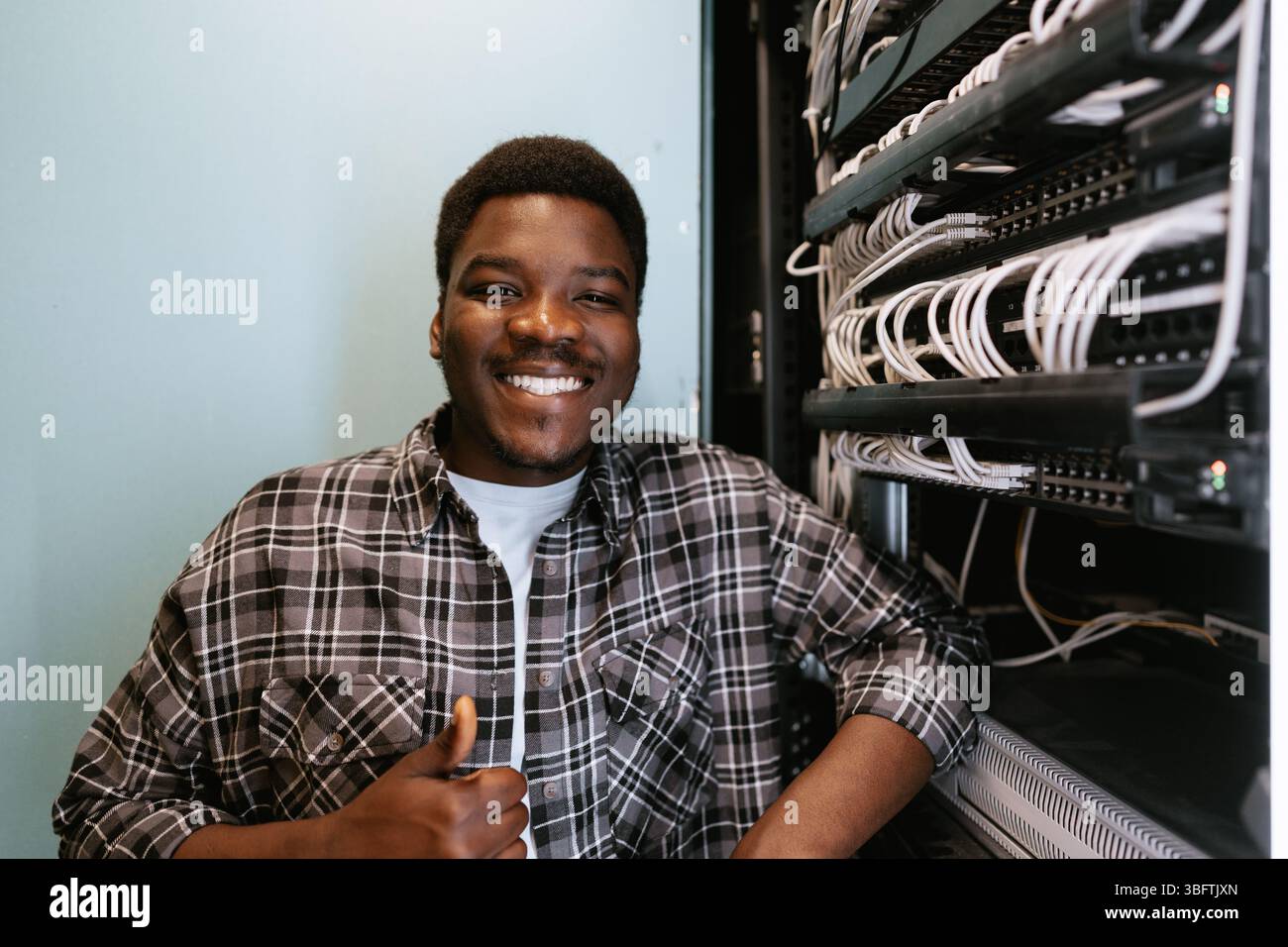 Young technician smiling confidently while working in server room Stock Photo