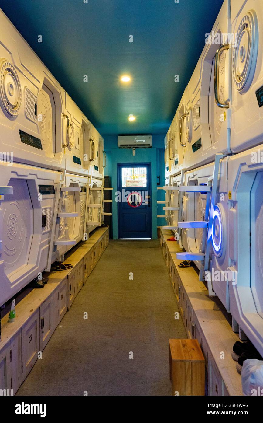 Bali, Indonesia - Dec 10, 2024: Row of white bunk beds with blue doors and a blue ceiling. The beds are in a hallway with a blue door Stock Photo