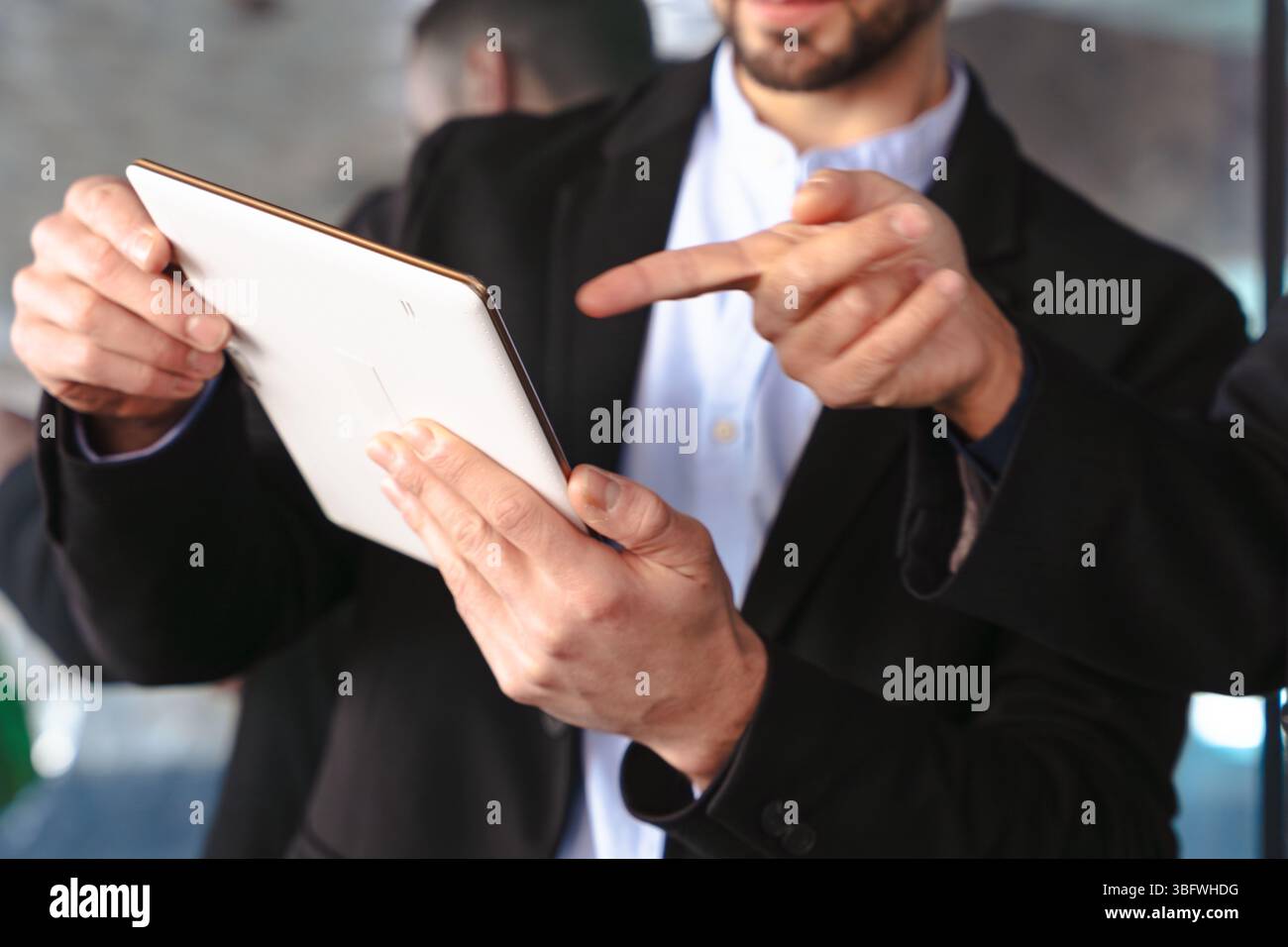 Unrecognizable businessmen in formal suits using a tablet during a ...