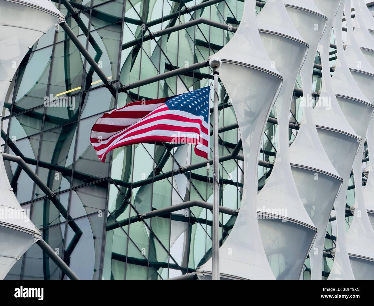LONDON, ENGLAND – MARCH 23, 2025: The US Embassy in London displays a modern architectural facade with the American flag prominently flying outside. - Smartphone Captured Stock Image