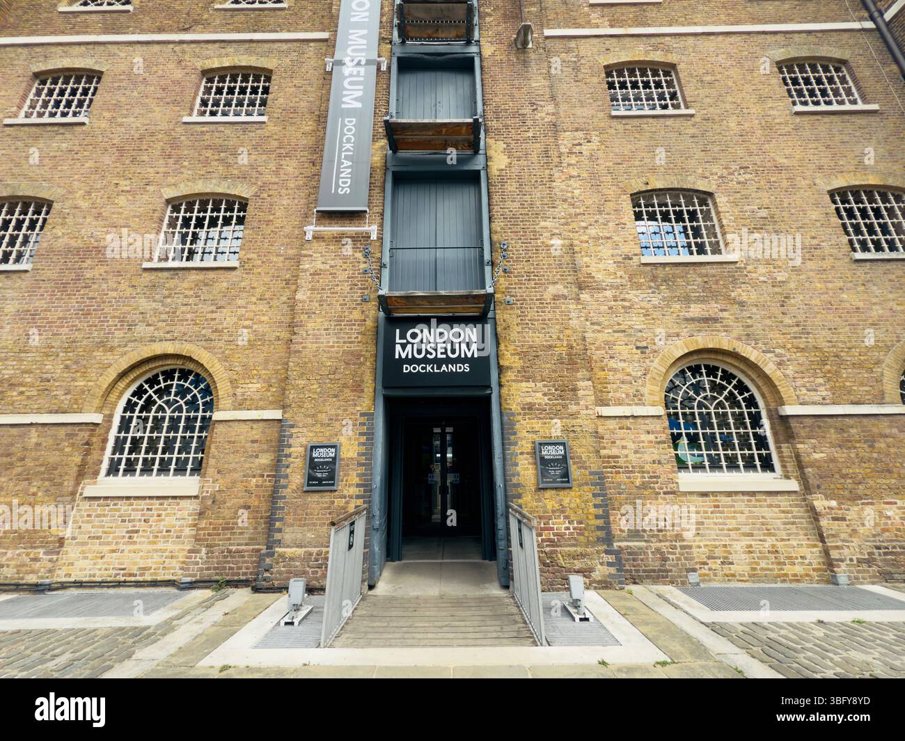 London, England – May 4, 2025: The entrance of the London Museum Docklands showcasing its historic brick architecture. - Smartphone Captured Stock Image