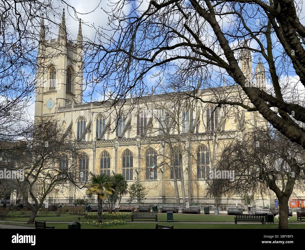 LONDON, ENGLAND – MARCH 16, 2025: St Luke's Church in Chelsea shown on a clear spring day surrounded by trees and benches, exemplifying Gothic Revival - Smartphone Captured Stock Image
