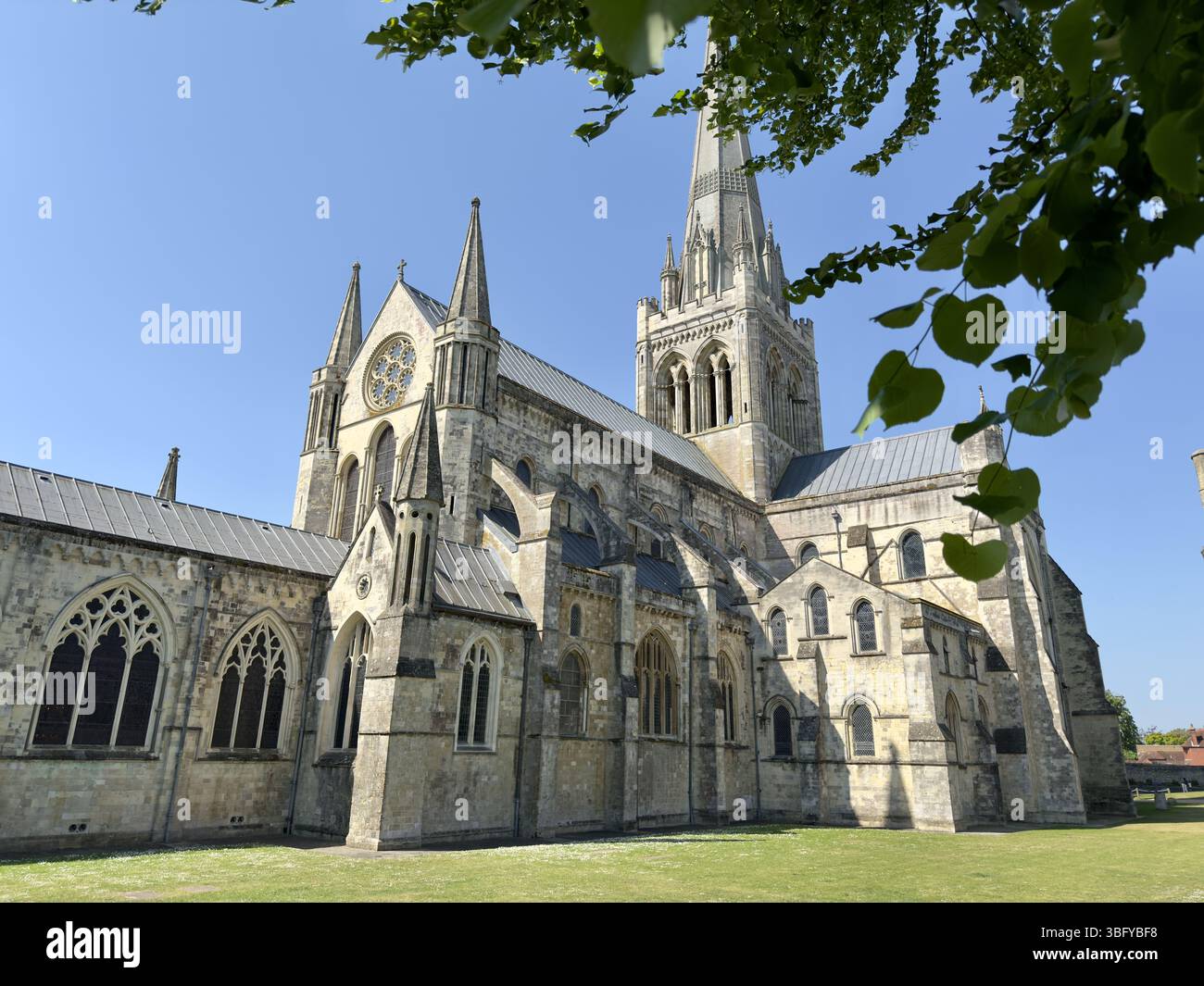 CHICHESTER, ENGLAND – MAY 14, 2025: Chichester Cathedral's Gothic architecture with a towering spire and intricate stonework, set against a clear blue - Smartphone Captured Stock Image