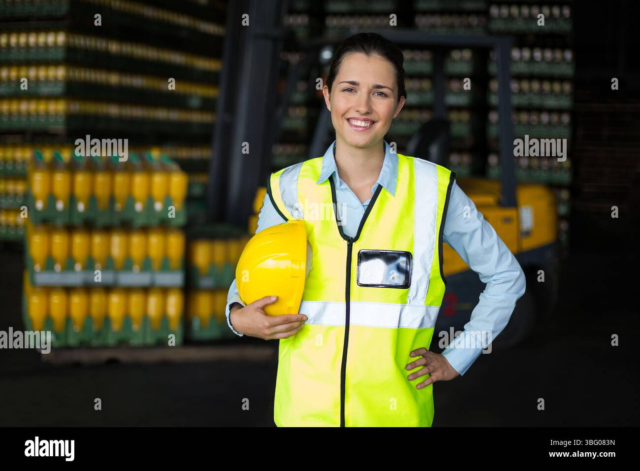 Female warehouse supervisor standing in storage wearing safety vest ...