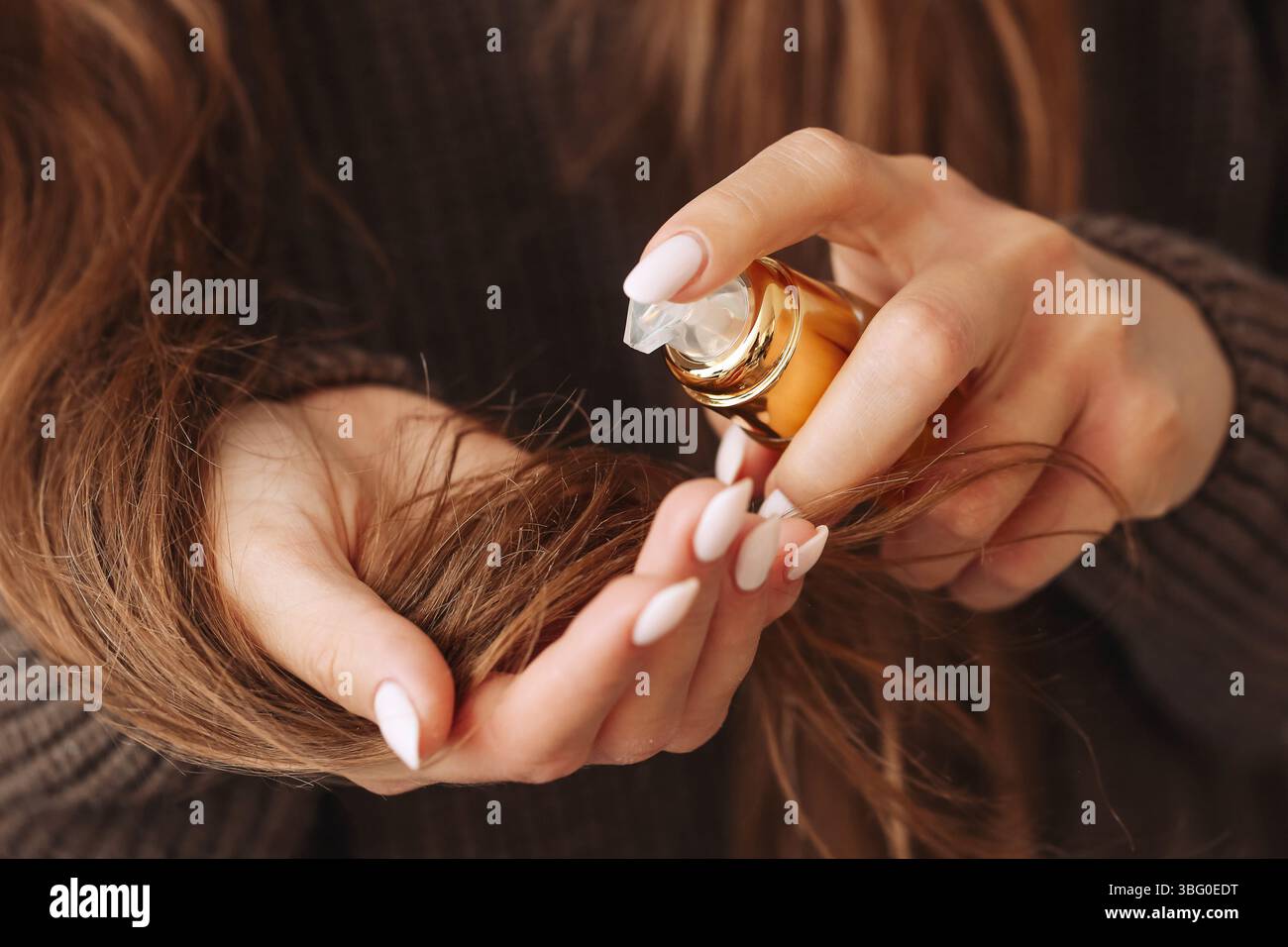 Woman applying oil to hair. Nourishing hair treatment. Natural hair care. Hand holding cosmetic oil. Hair beauty concept. Moisturizing organic oil. Stock Photo
