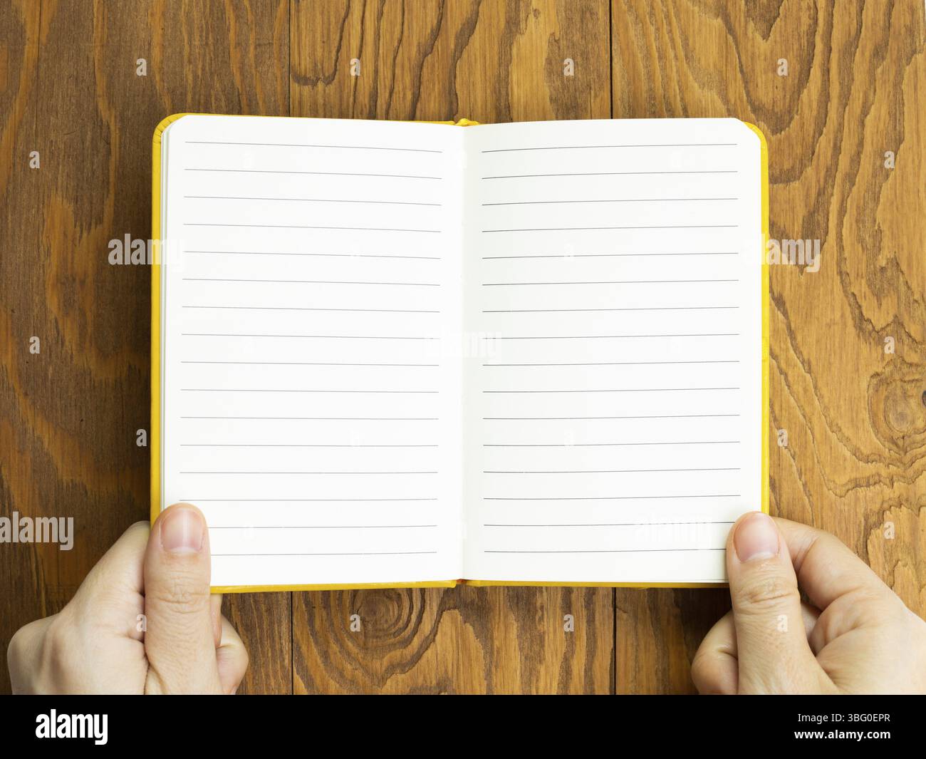 Hands open empty notebook on wooden desk. top view, copy space Stock Photo