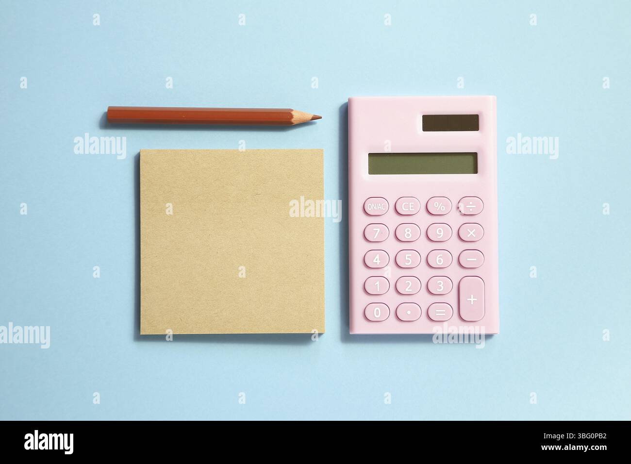 Pink digital calculator and memo note pad and brown colored pencil on blue background Stock Photo