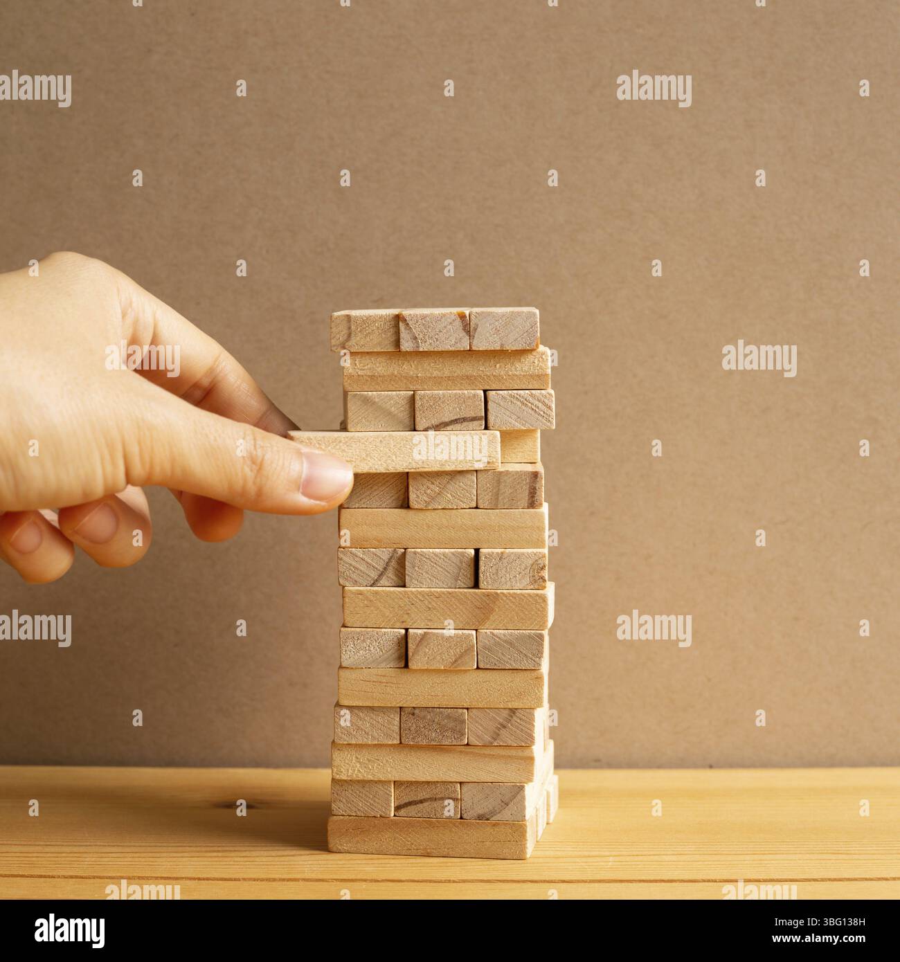 Jenga wood block tower with brown background. Block stack game ...