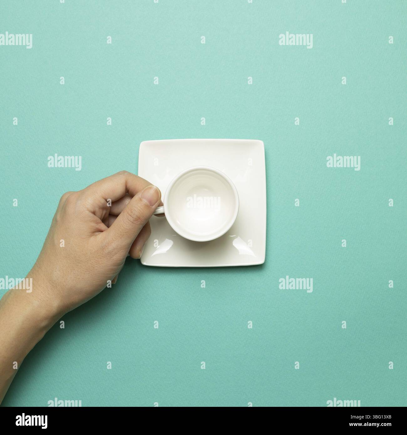 Female hand holding white empty mug cup on mint green background. top view Stock Photo