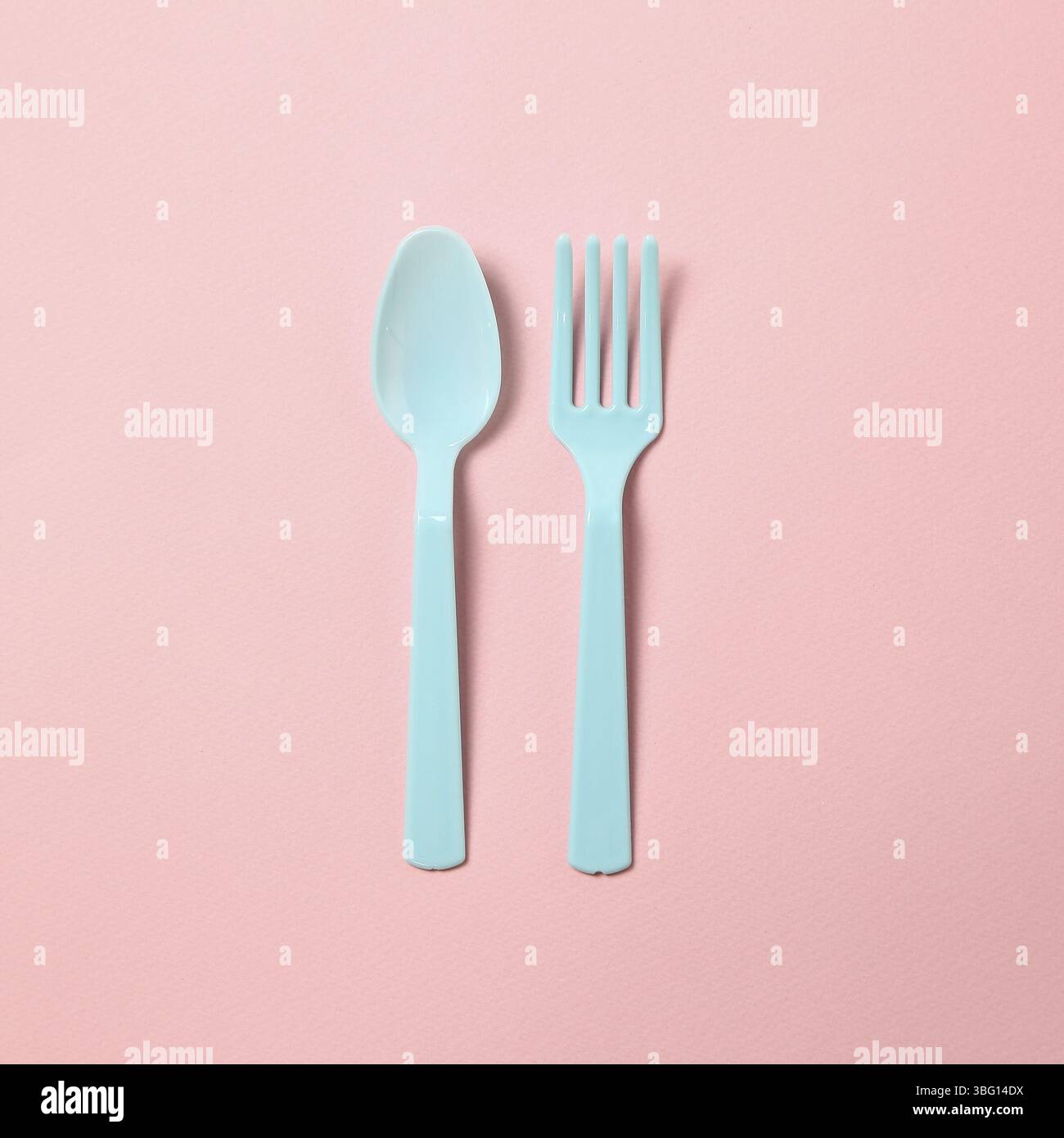 Blue plastic fork and spoon isolated on pink background Stock Photo