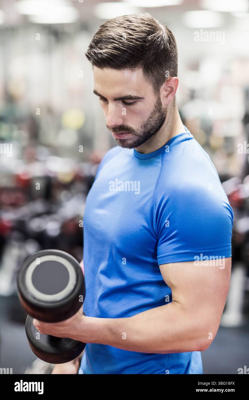 Male weightlifter performing bicep curl with dumbbell at gym wearing ...