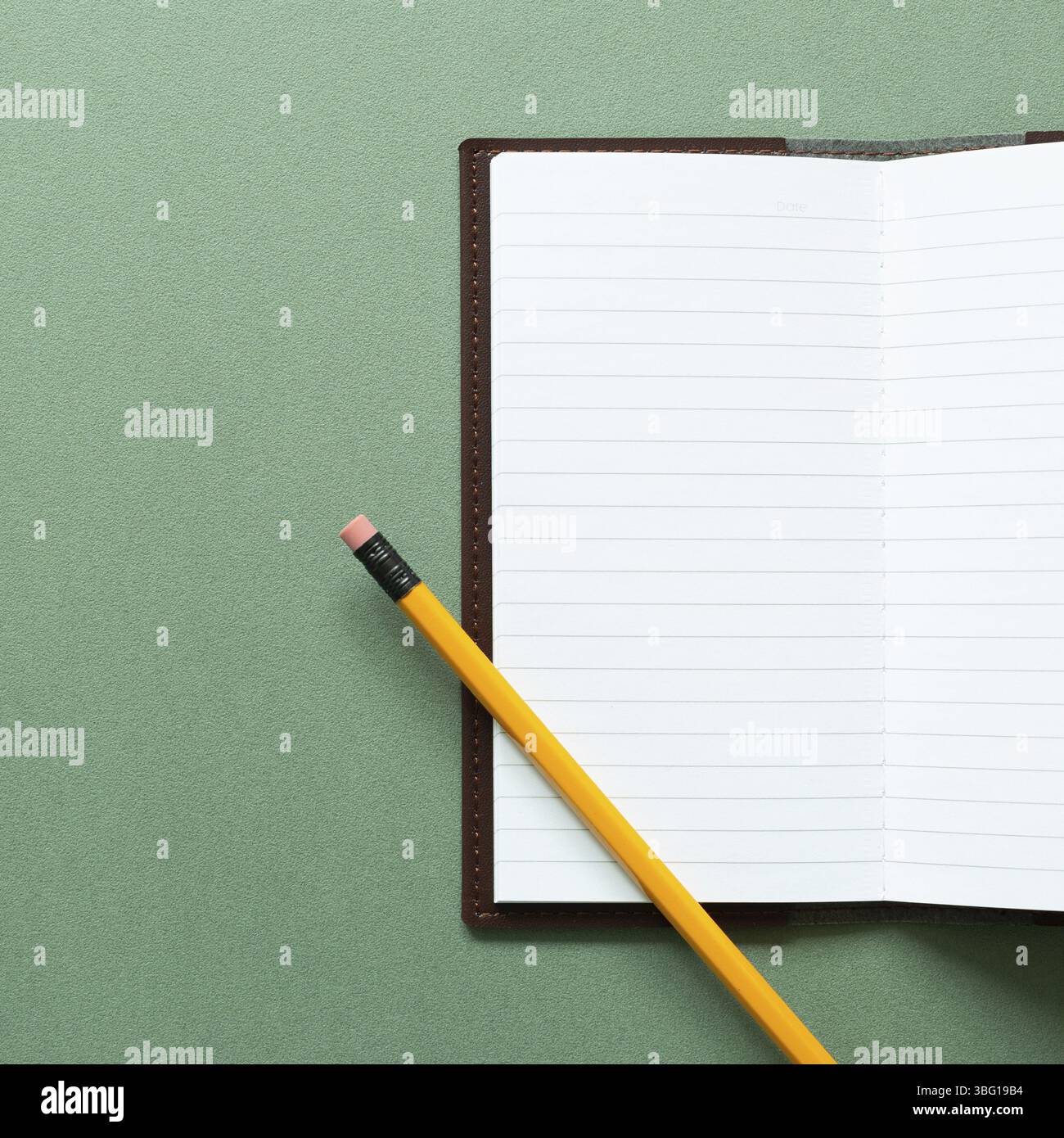 Open notebook and pencil on green background. top view, copy space Stock Photo
