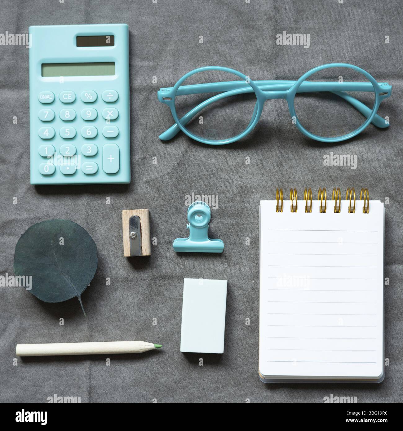 Mint calculator, eyeglasses, notebook and office supply on gray fabric background. flat lay, top view Stock Photo