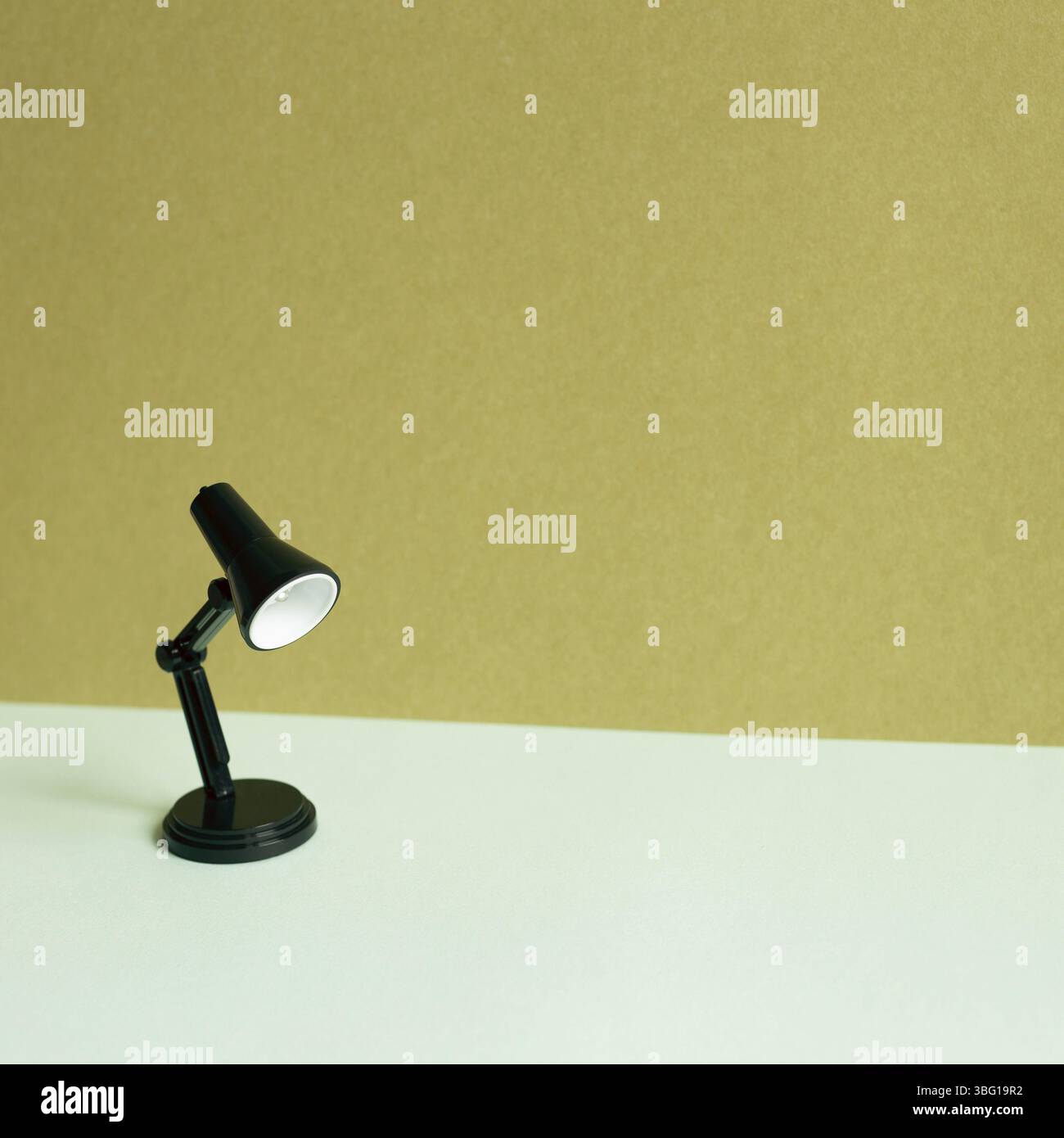 Black desk lamp on sky blue desk. khaki wall background Stock Photo