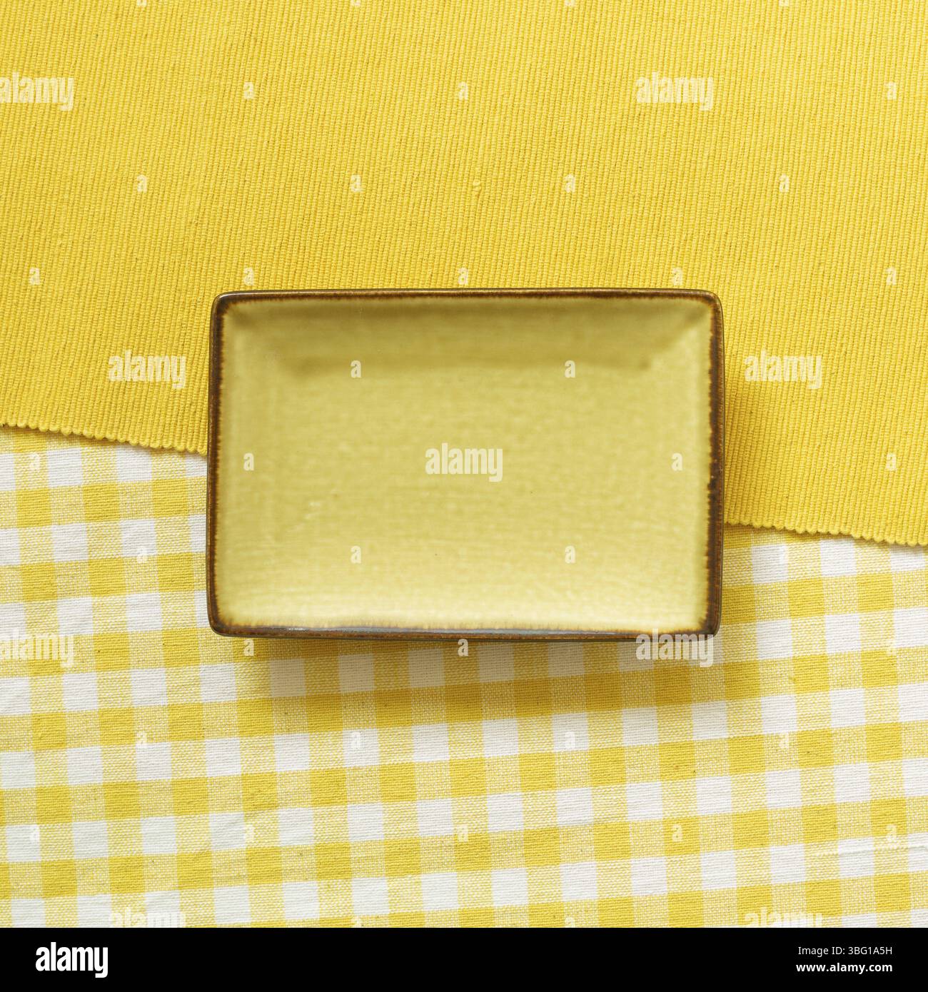 Empty plate on yellow fabric background. top view Stock Photo