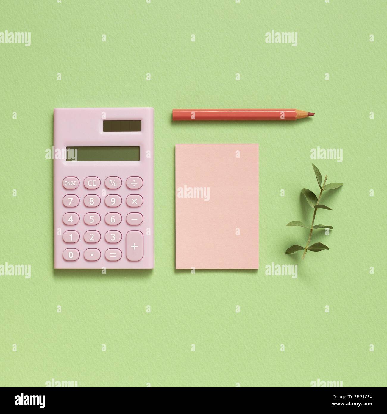 Pink digital calculator and memo note pad and colored pencil on pastel green background Stock Photo