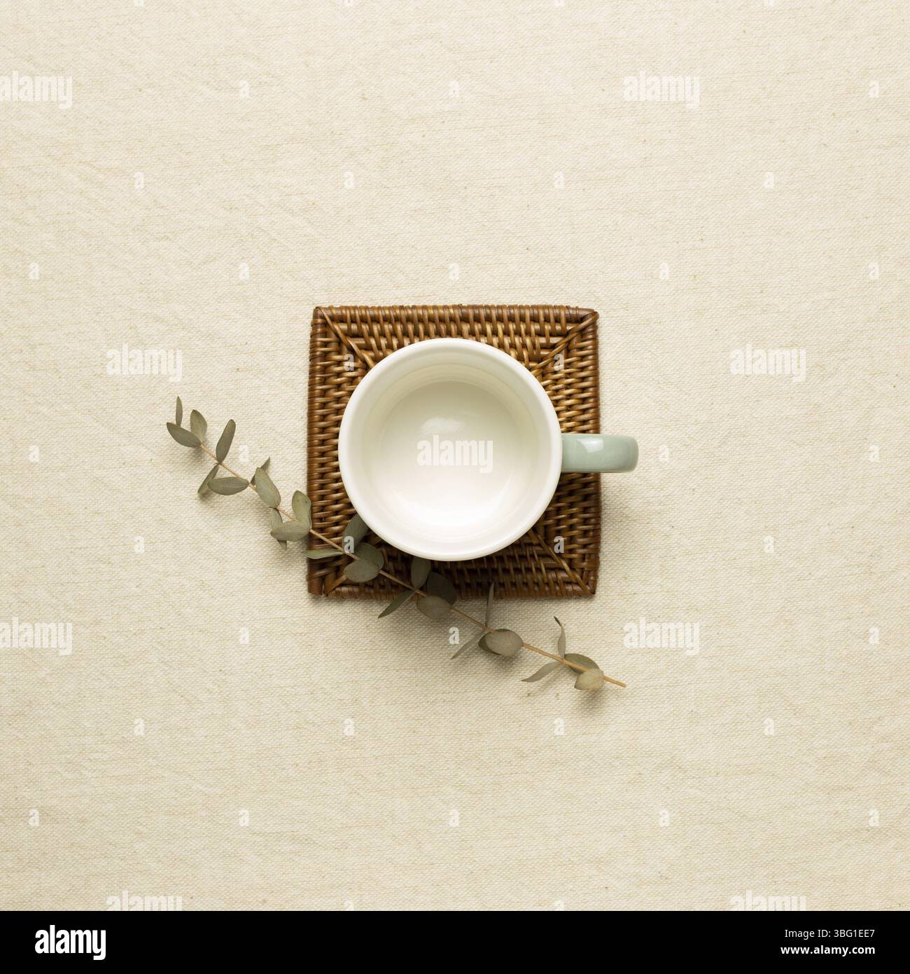 Empty mug cup with eucalyptus leaf on beige fabric background. top view Stock Photo
