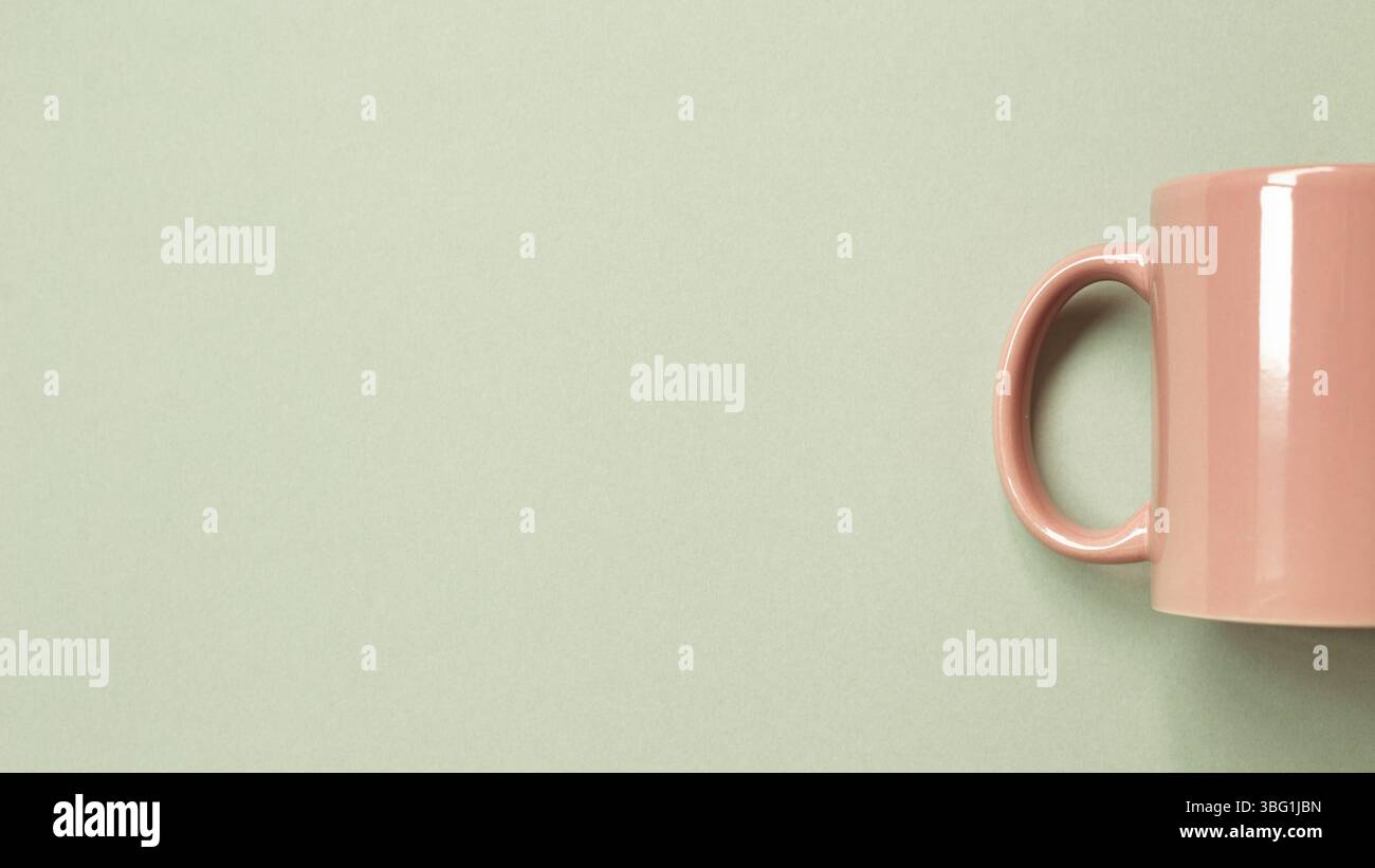 Pink mug cup on green background. copy space Stock Photo