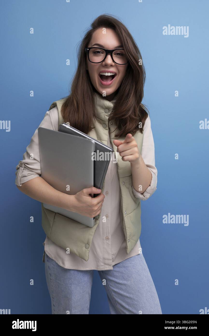 Positive 30s lady student holding documents and laptop on empty space background Stock Photo