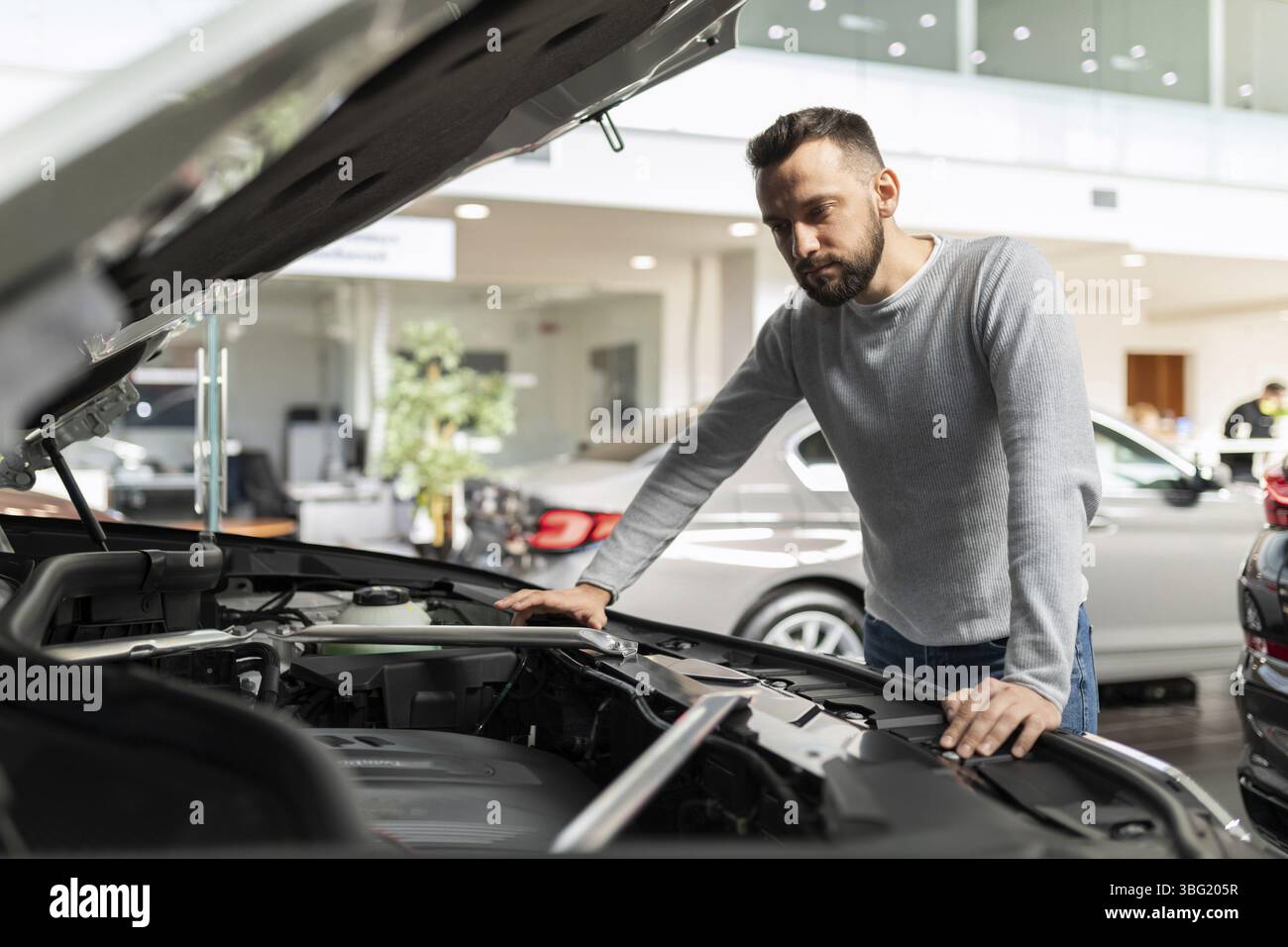 Ein mann in einem autohaus untersucht einen automotor vor dem kauf Stock Photo