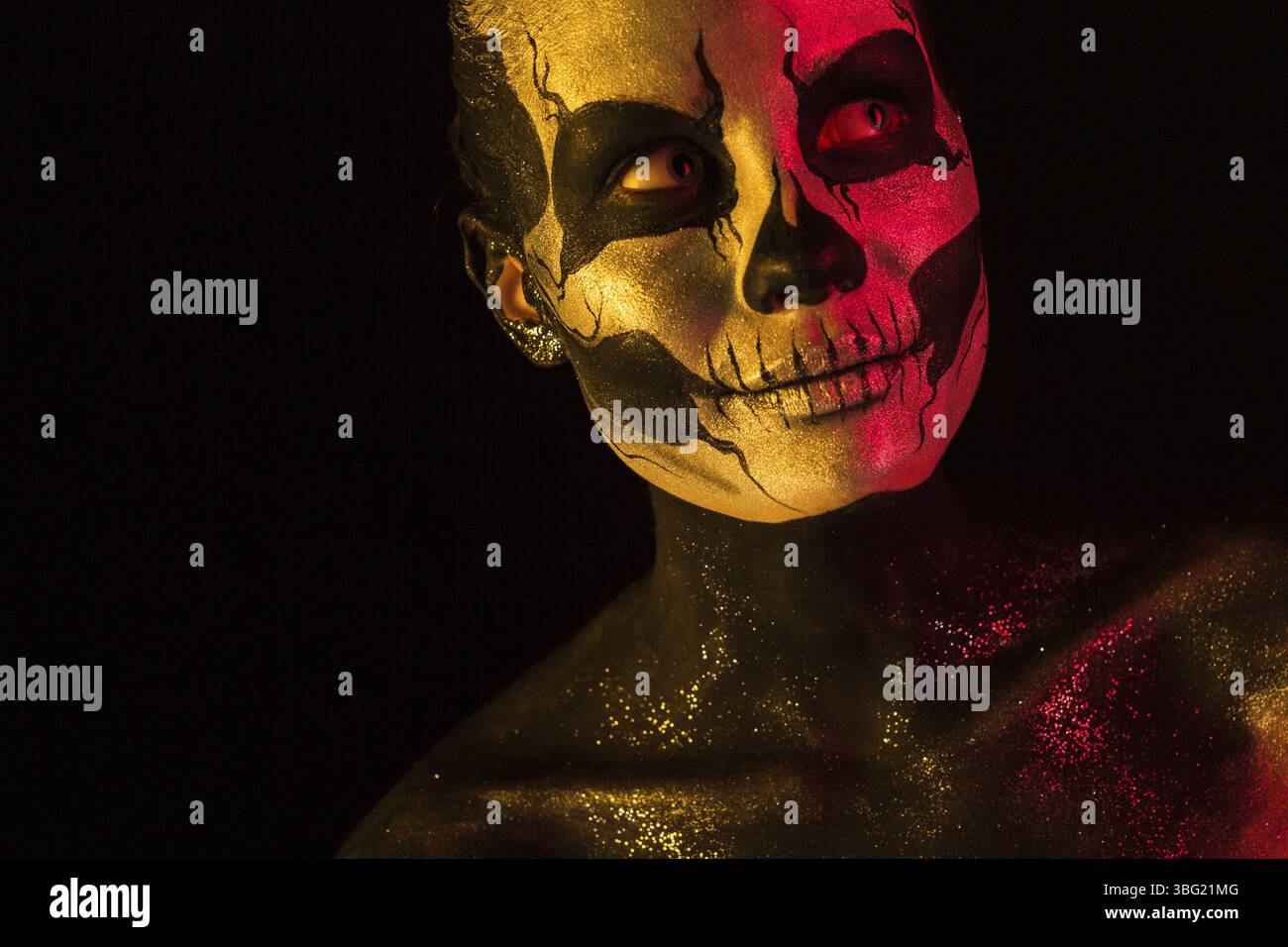 Isolated on black, closeup picture, toned red and yellow, beautiful young blonde caucasian woman with scull body art, grey eyes Stock Photo