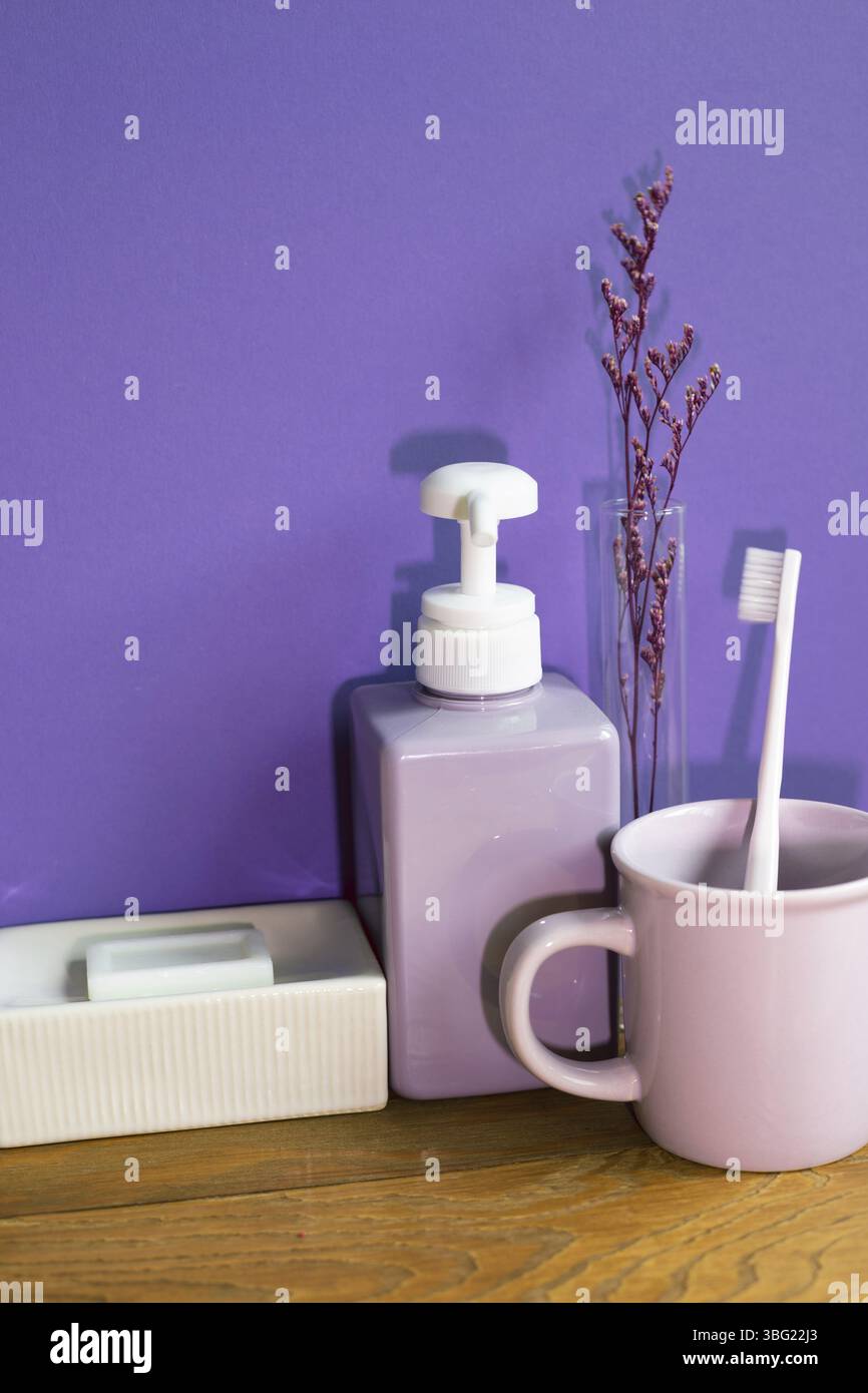 Bathroom accessories hygiene objects on wooden table. purple wall background Stock Photo