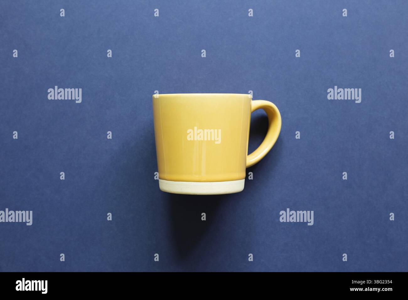 Yellow mug cup on blue background. top view, copy space Stock Photo
