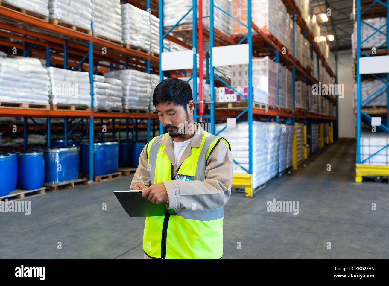 Someone Inspecting Inventory Asian man in his 30s wearing safety vest inspecting inventory with ...