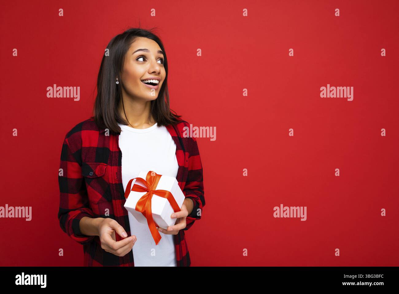 Photo of positive happy smiling young fascinating beautiful attractive nice brunette woman with sincere emotions wearing casual white t-shirt and red Stock Photo