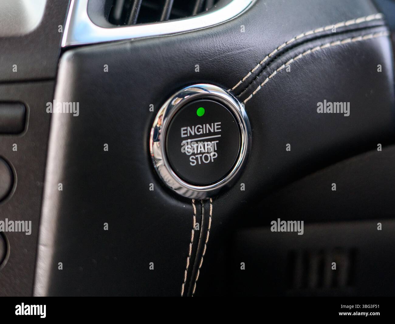 This image highlights a sleek engine start/stop button inside a modern vehicle, typically located on the dashboard, offering keyless ignition function Stock Photo