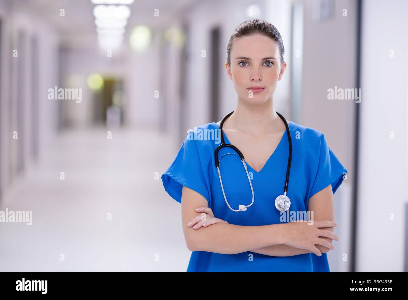 Female nurse standing with crossed arms in hospital corridor wearing ...