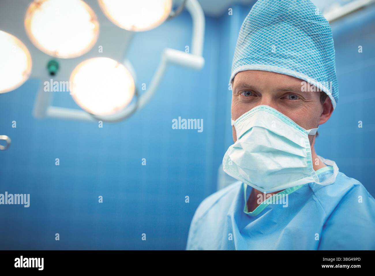 Male surgeon standing in operating room under surgical lights wearing ...