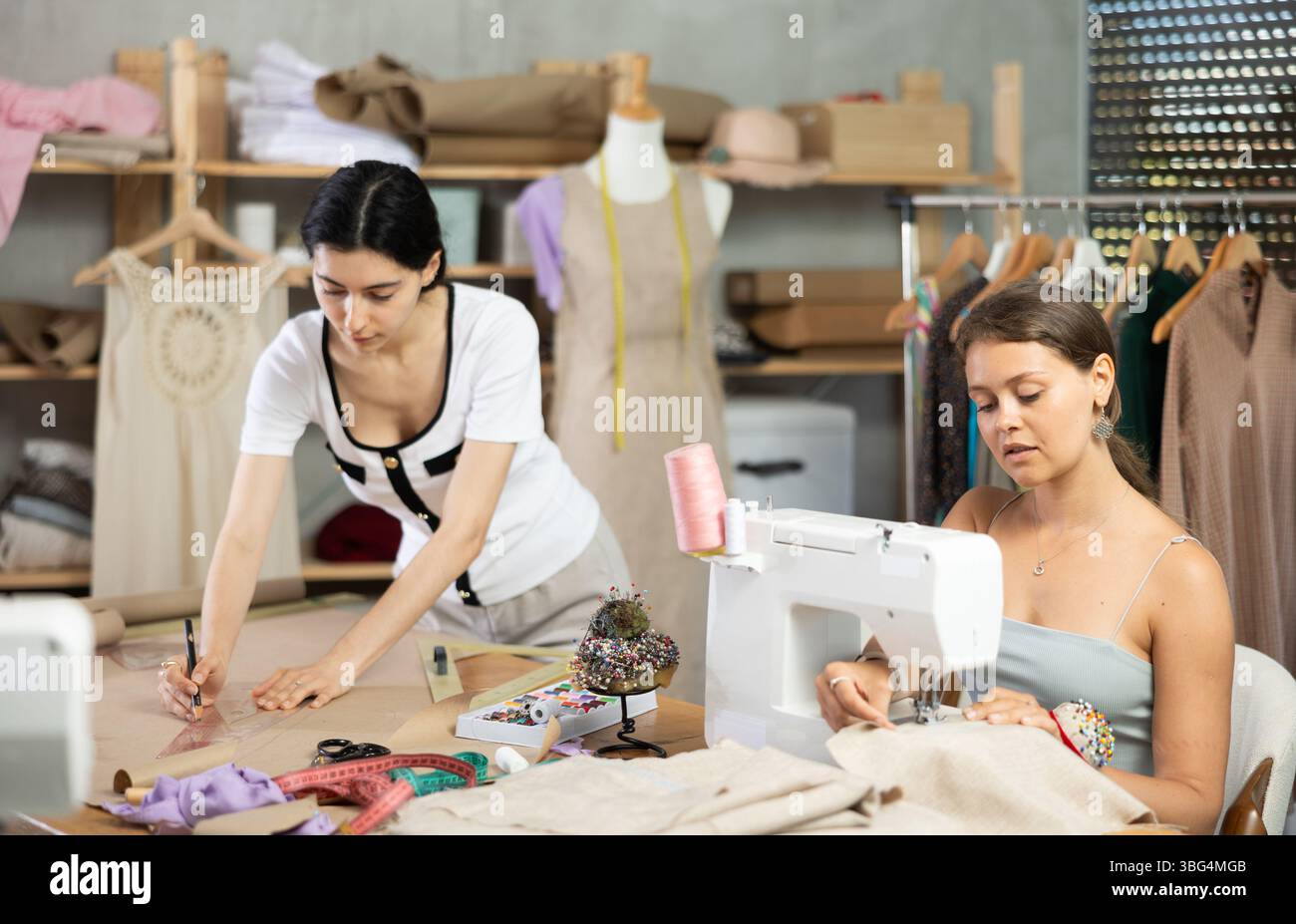 Young seamstresses stitching and drafting paper patterns in workshop Stock Photo