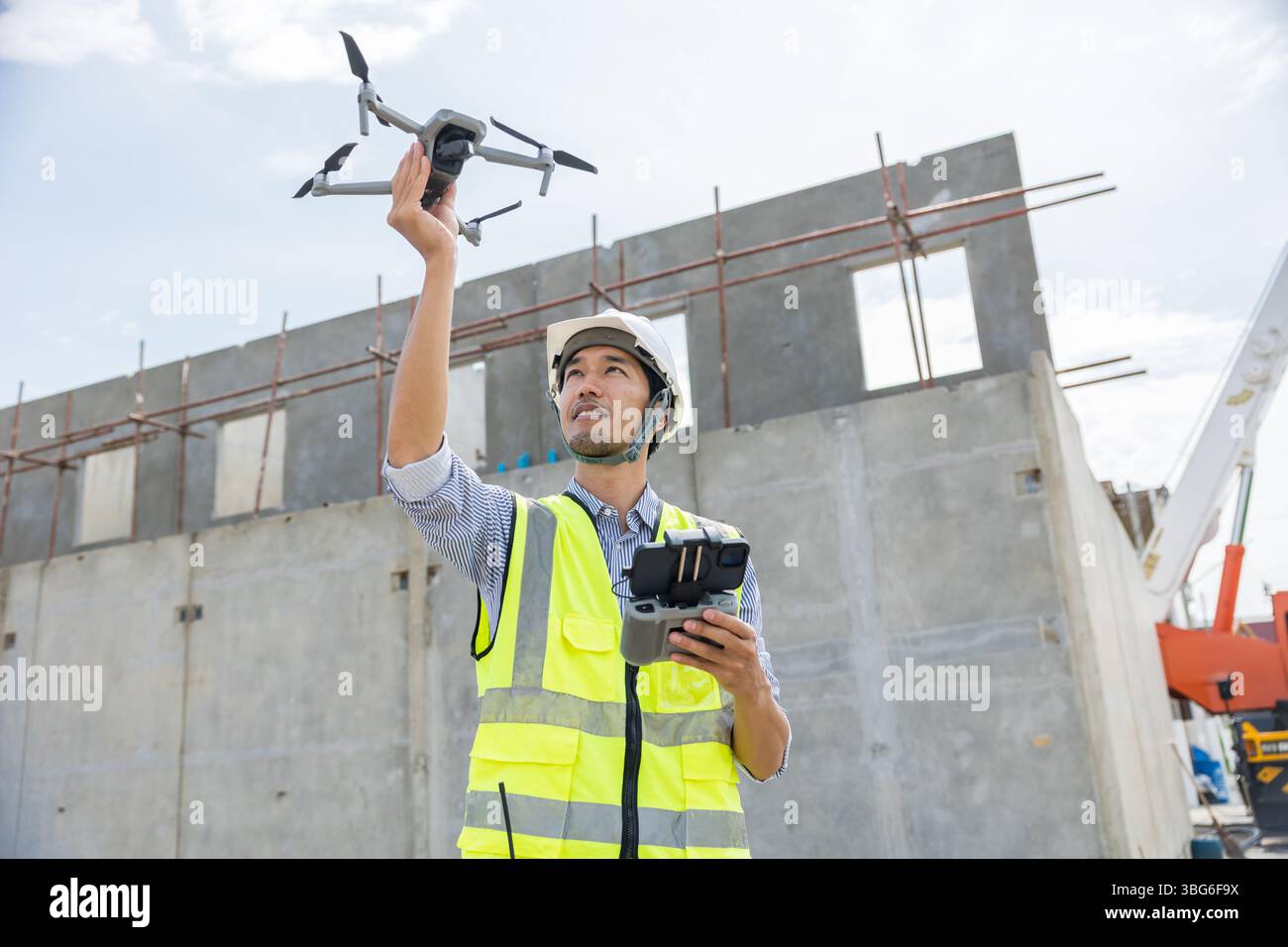 Professional construction engineer builder using UAV Drone technology device to help assist inspecting construction site from aerial view Stock Photo