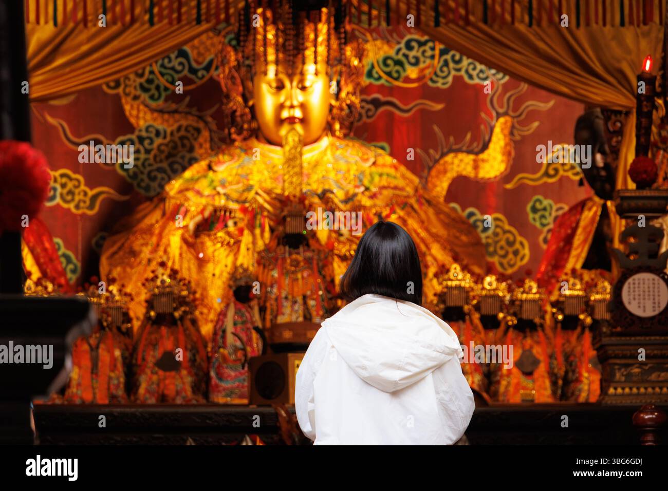Asian Chinese people praying, Make a wish in front of Mazu or Matsu golden statue in Taiwan Temple Stock Photo