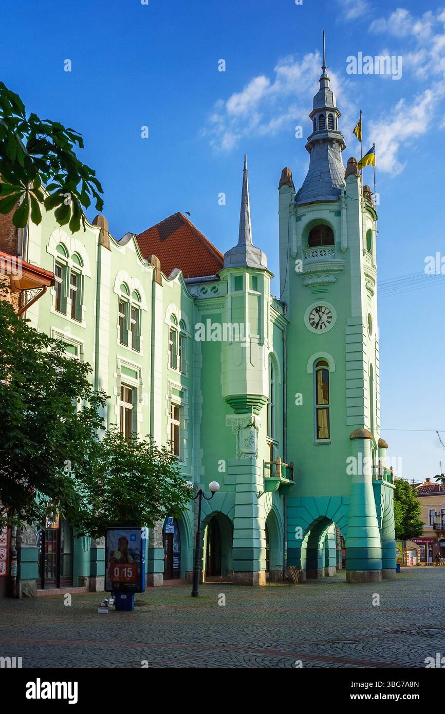 mukachevo, ukraine - jun 16 2012: city council of the old town in morning light. green building with clock tower. popular travel attraction in the cit Stock Photo