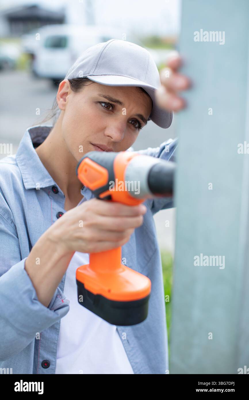 young female builder drilling a hole in the wall Stock Photo