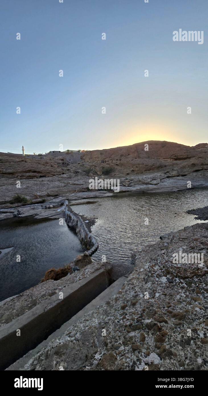 A scenic view of Wadi Hibi in Oman, showcasing the rugged rock formations and clear water flowing through the wadi. - Smartphone Captured Stock Image