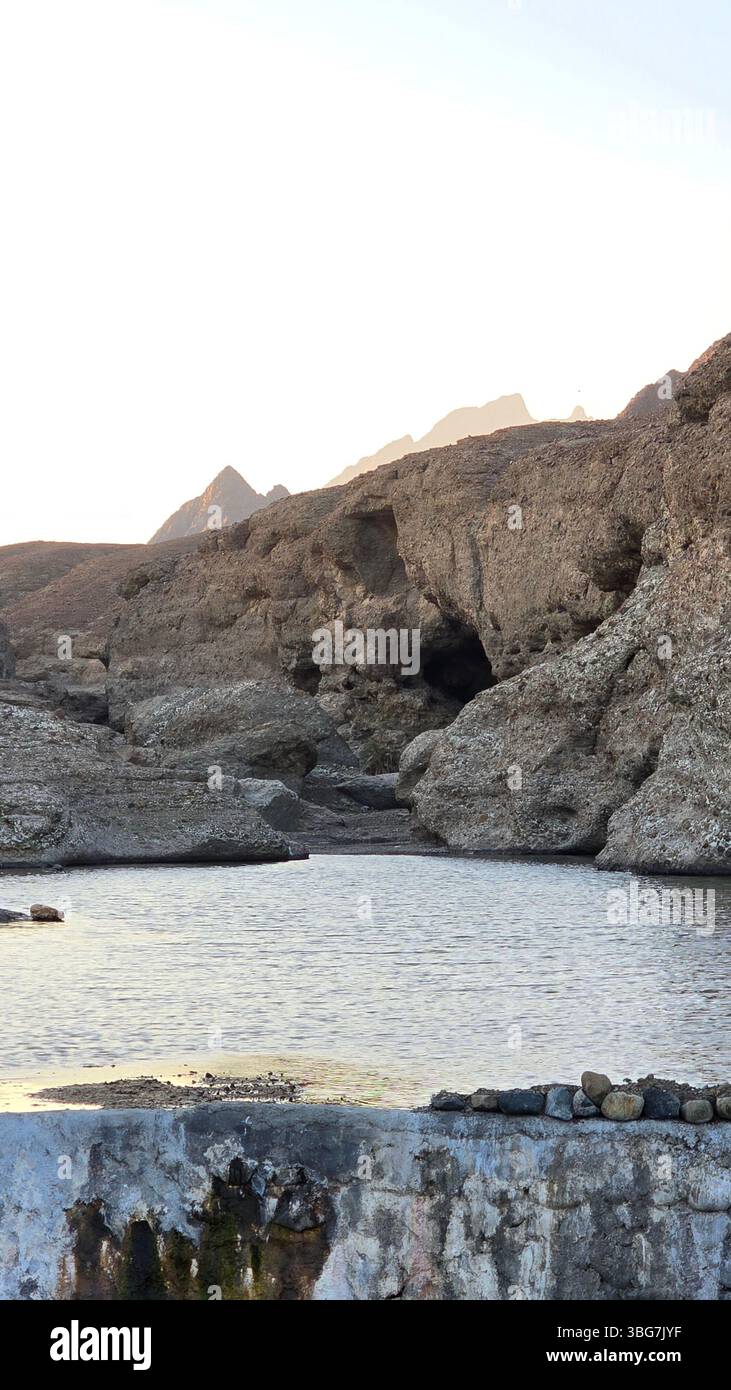 A scenic view of Wadi Hibi in Oman, showcasing the rugged rock formations and clear water flowing through the wadi. - Smartphone Captured Stock Image