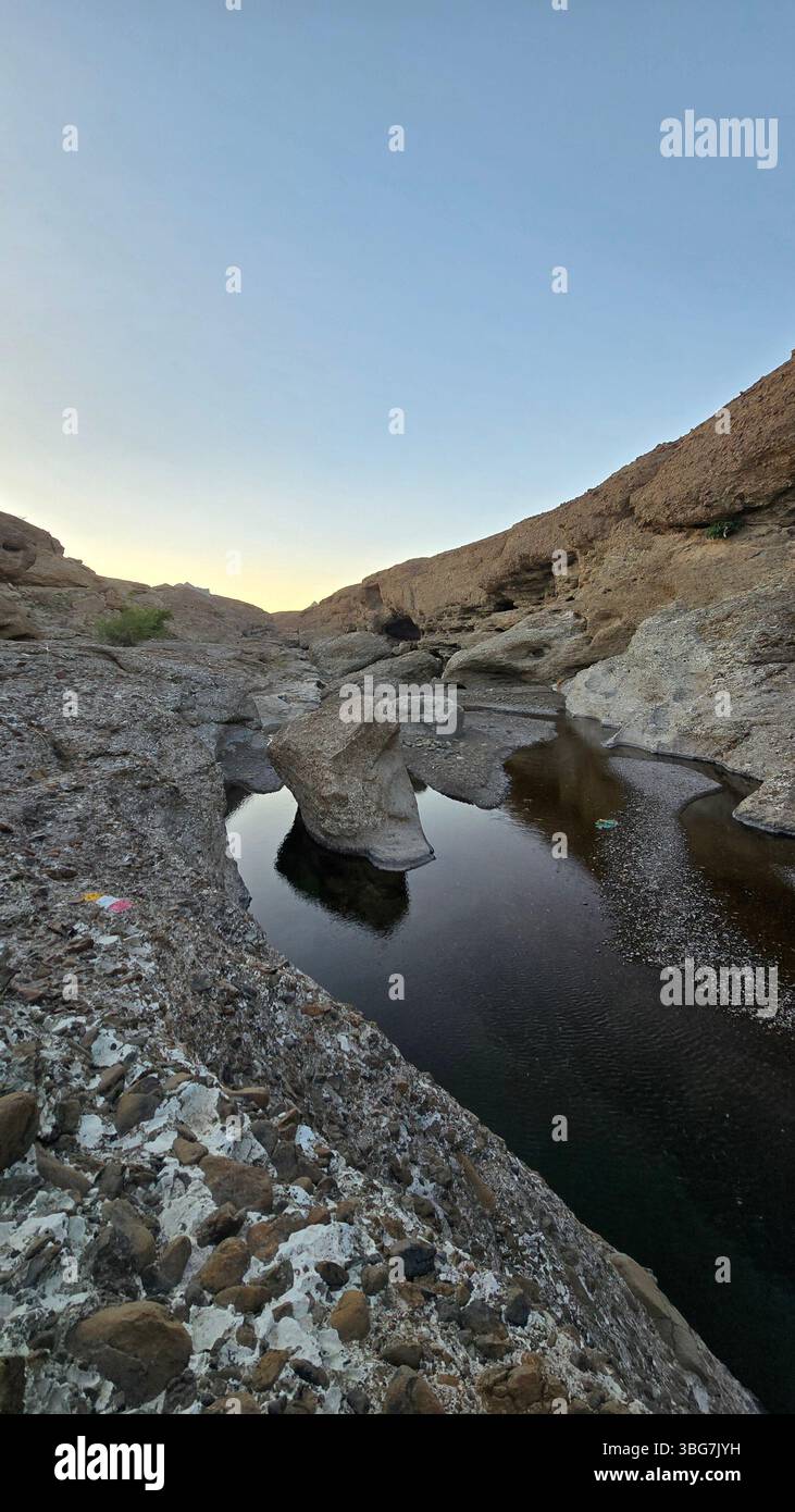 A scenic view of Wadi Hibi in Oman, showcasing the rugged rock formations and clear water flowing through the wadi. - Smartphone Captured Stock Image