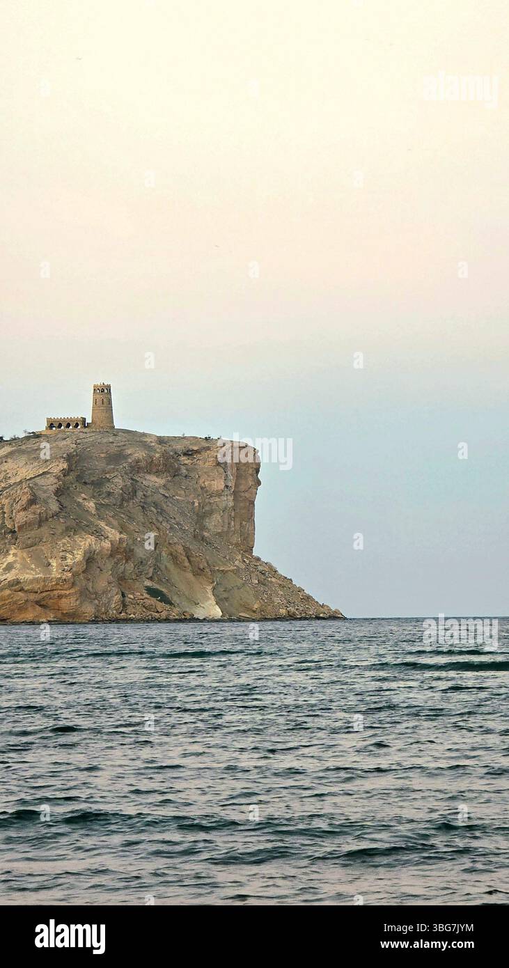 A historic fort perched atop a rocky outcrop overlooking the scenic Al-Sawadi Beach in Al Batinah North Governorate, Oman - Smartphone Captured Stock Image