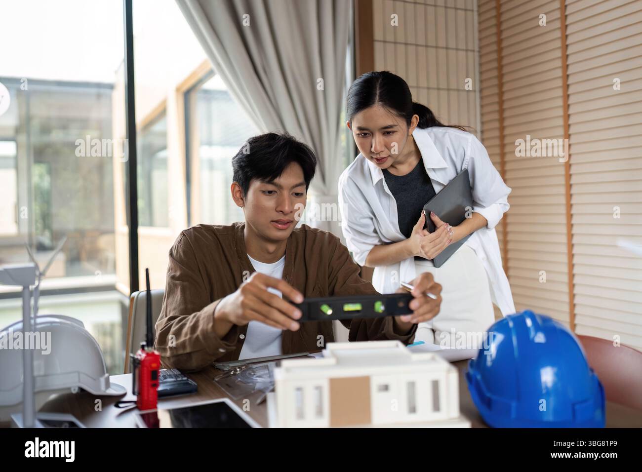 ESG Principles in Action. Architects reviewing a building model for sustainable construction. Stock Photo